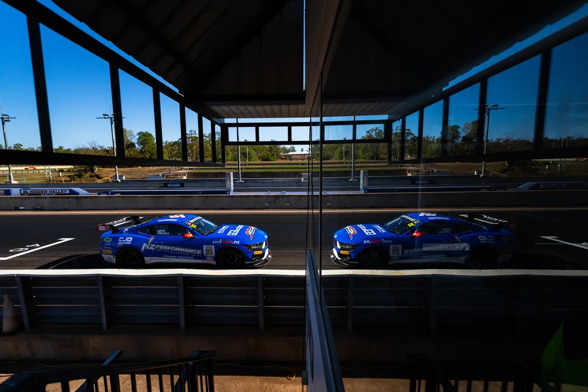 The #95 Ford Mustang GT4 in the Hidden Valley pit lane, reflected in the garage glass