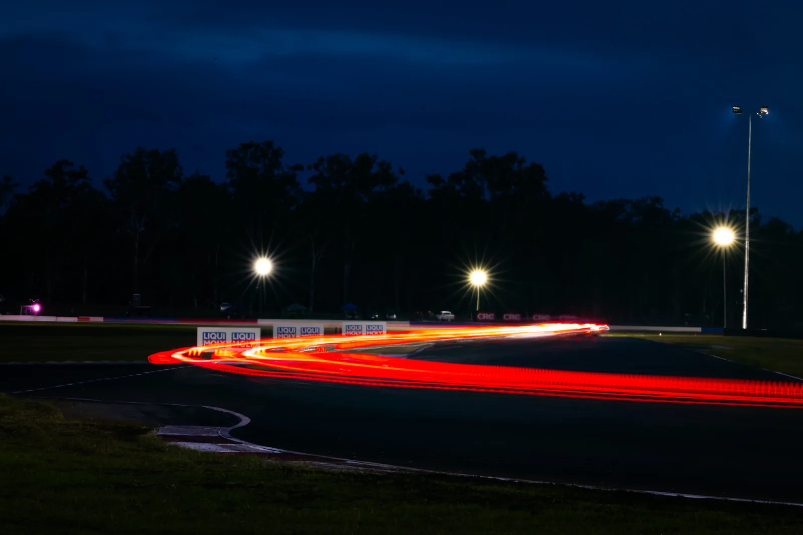 Long-exposure light trails through the corner during the Queensland Raceway night race