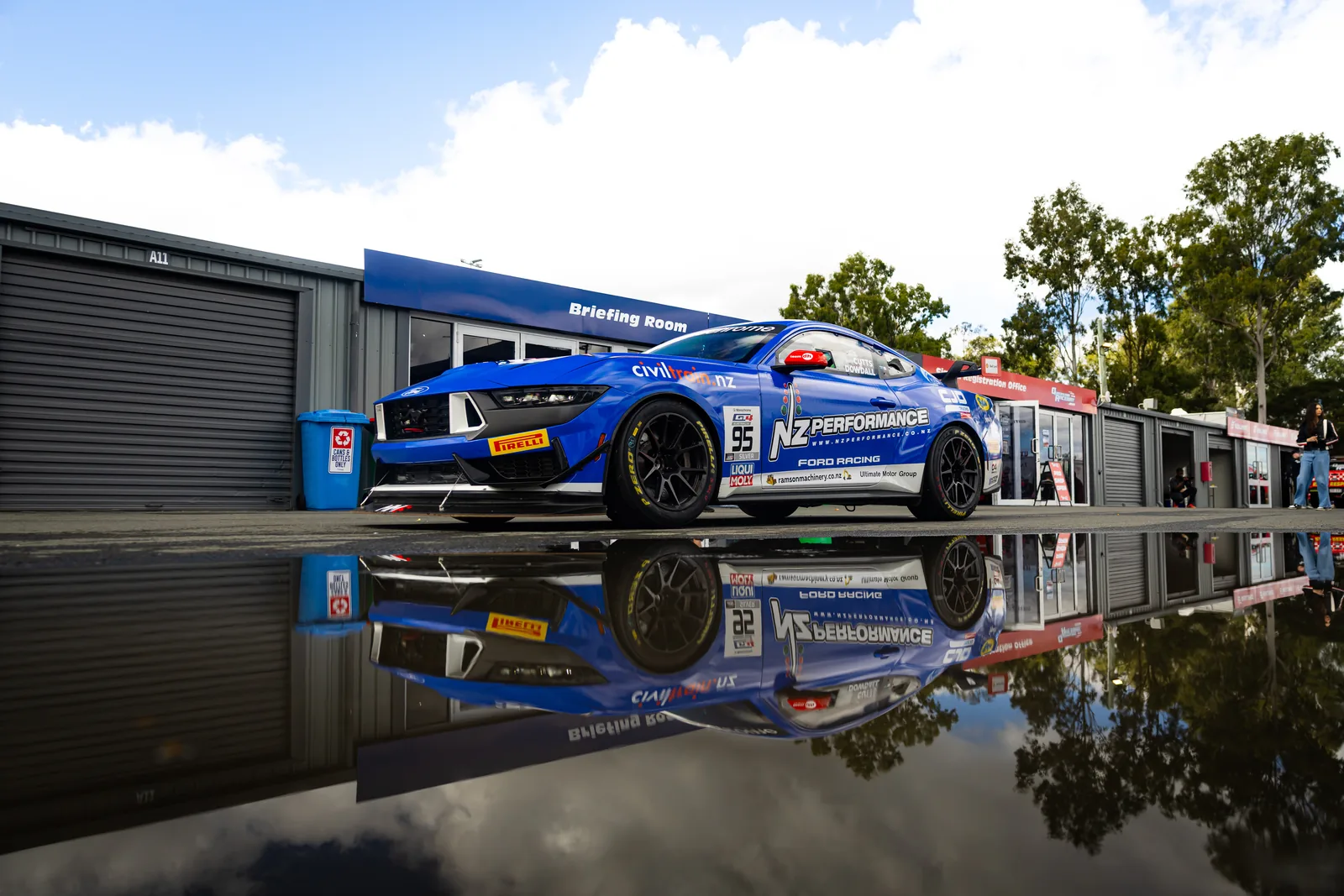 The #95 Ford Mustang GT4 reflected in a pit lane puddle at Queensland Raceway
